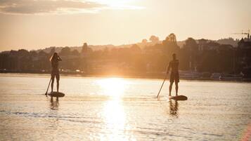 Due persone che fanno paddleboarding su acque calme al tramonto.