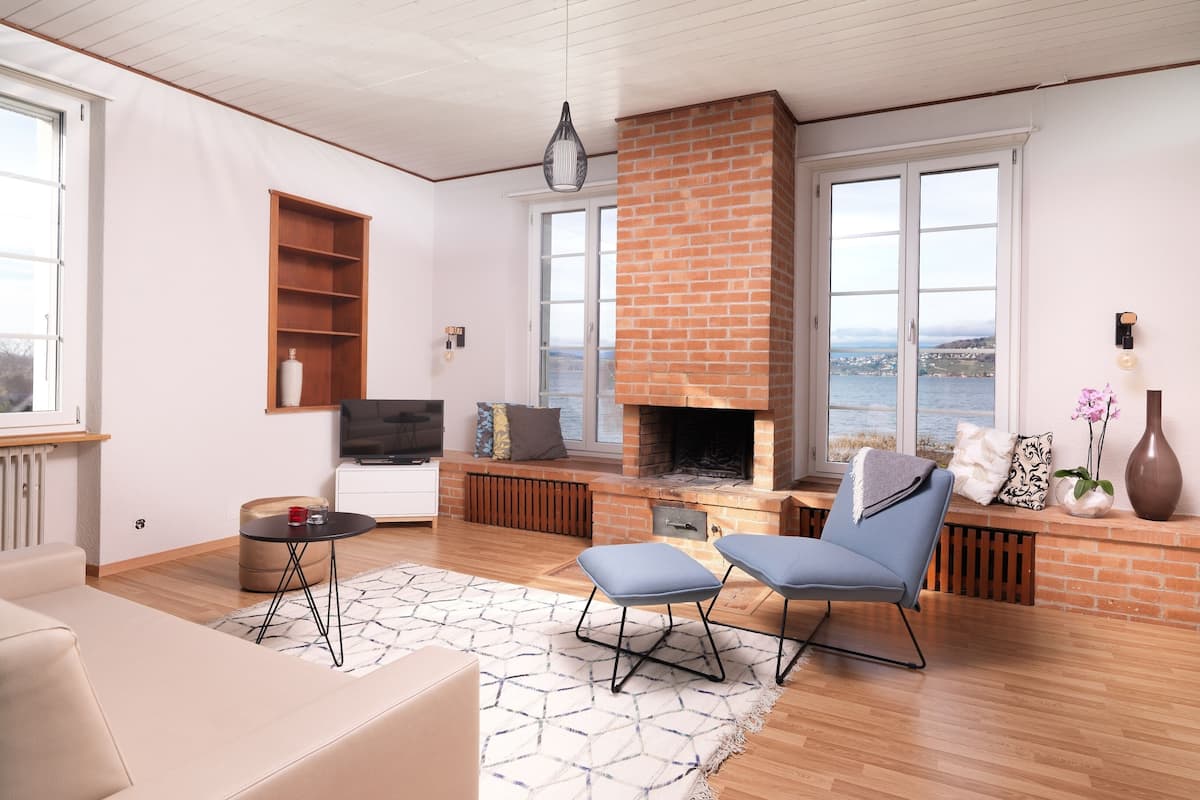 Una sala de estar moderna con chimenea, televisor y vistas al mar.