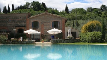 Una piscina al aire libre, sombrillas, sillones reclinables de piscina