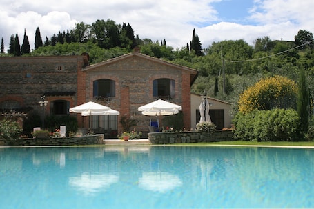 Una piscina al aire libre, sombrillas, sillones reclinables de piscina