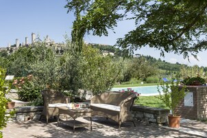 Una terrazza esterna con mobili in vimini, un tavolo in pietra e una pianta in vaso.