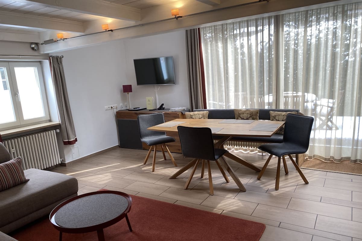 Ein modernes Wohnzimmer mit einer Couch, einem runden Couchtisch und einem Essbereich mit Tisch und Stühlen.