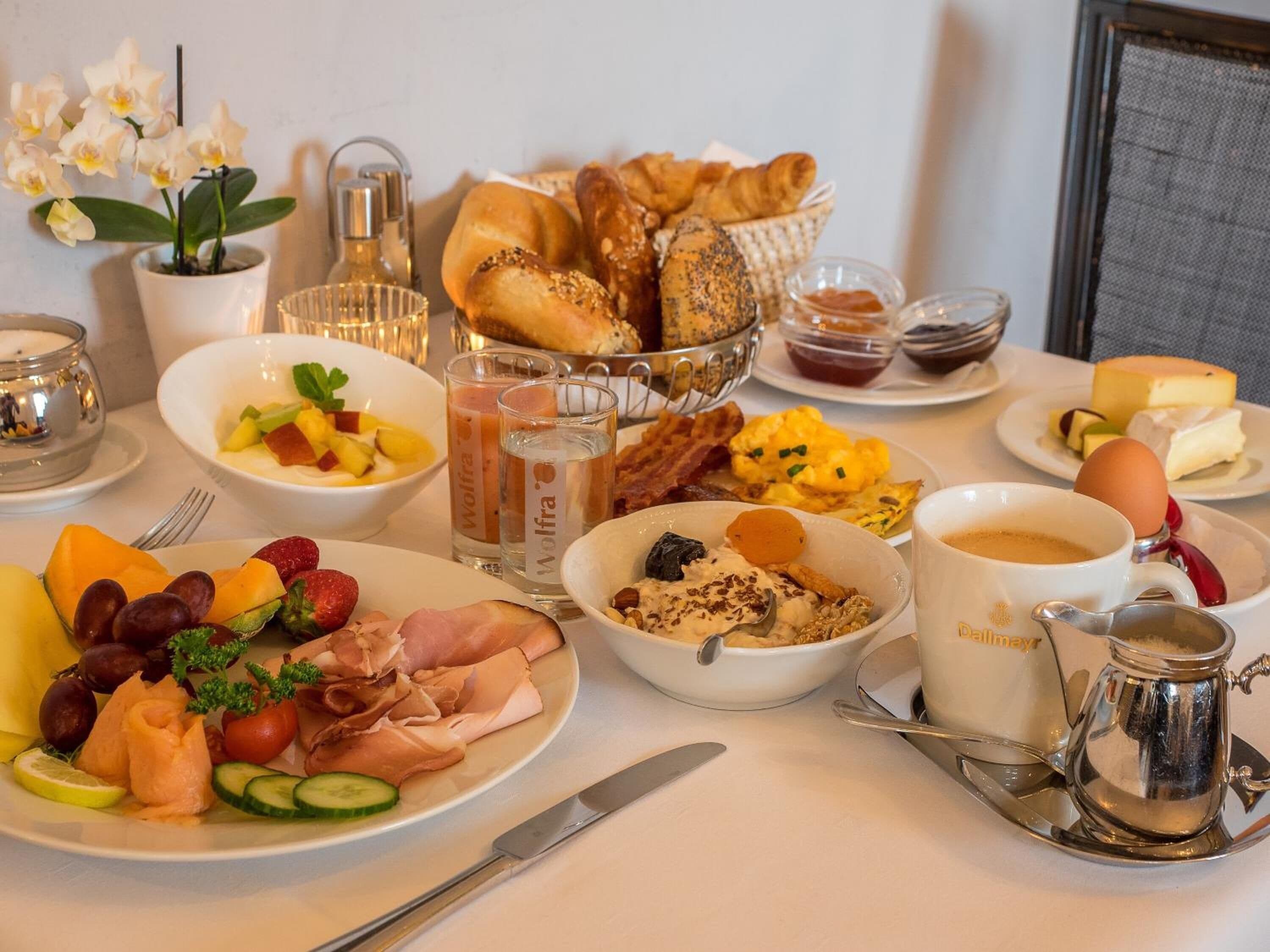Un bufé de desayuno con diversos platos, como frutas, carnes y pasteles.