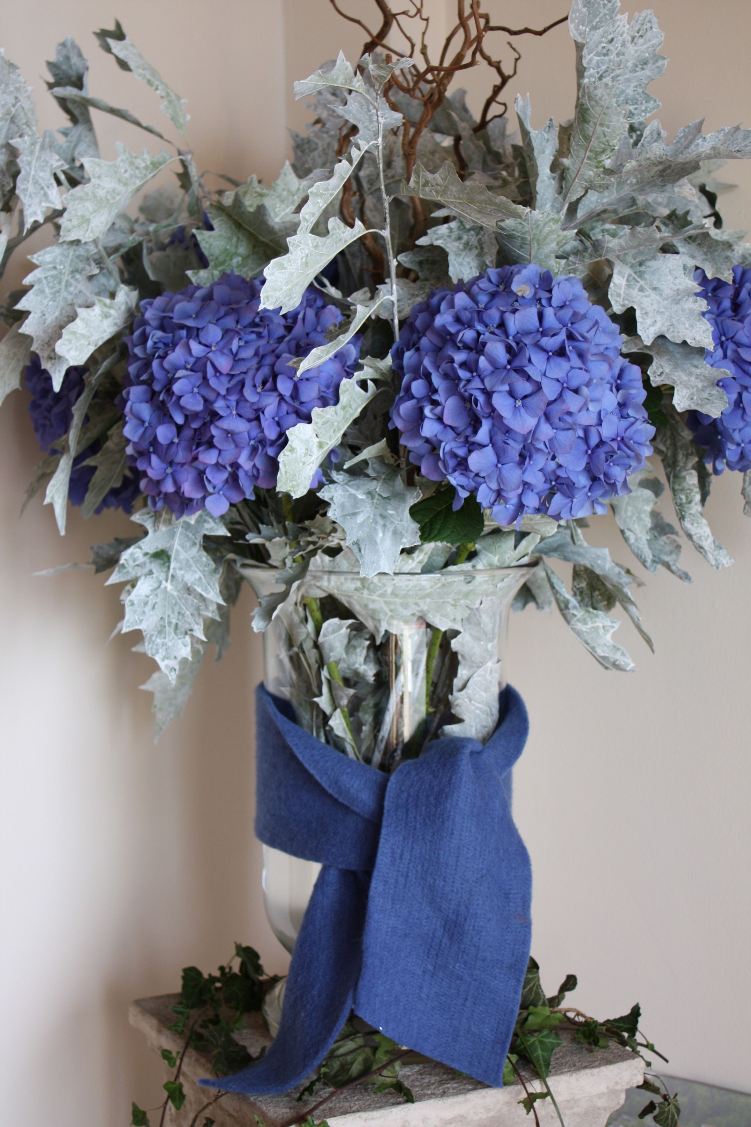A vase with blue flowers and a blue ribbon.