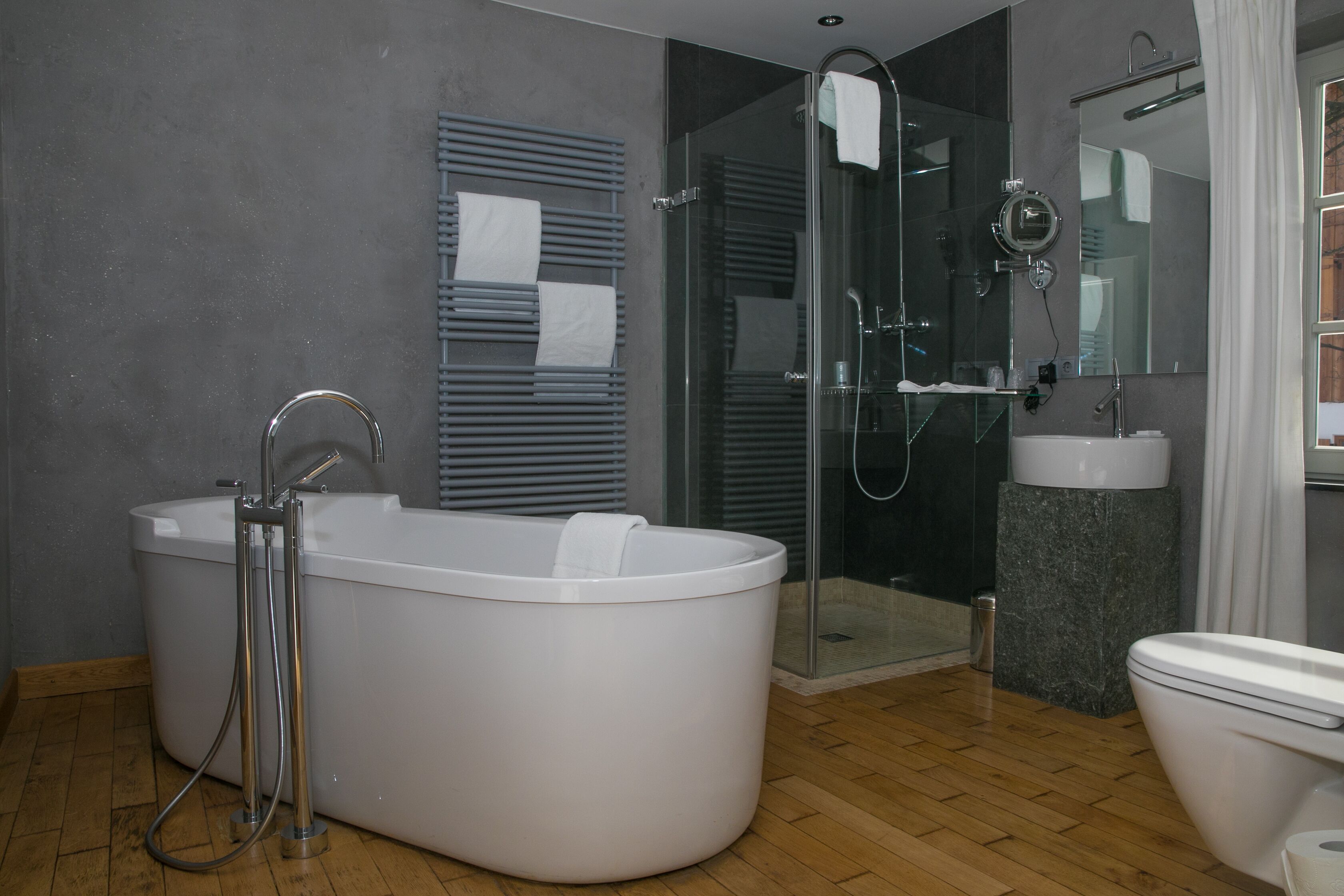 Ein modernes Badezimmer mit freistehender Badewanne, einer gläsernen Duschkabine und einem separaten WC.