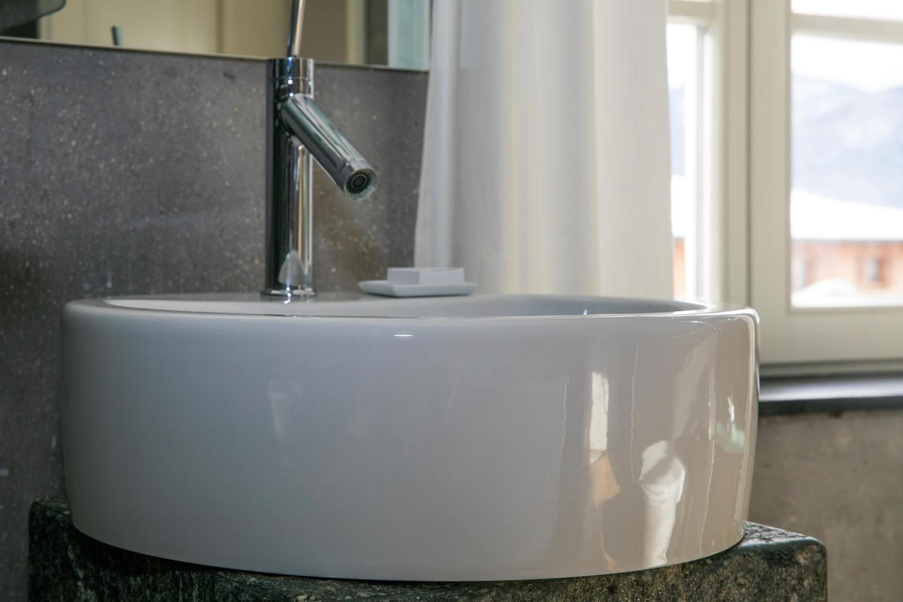 A white ceramic sink with a modern faucet mounted on a granite countertop.