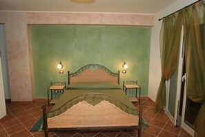 A bedroom with a bed, two bedside tables, and a window with curtains. - Sikania Suite (Pozzallo)