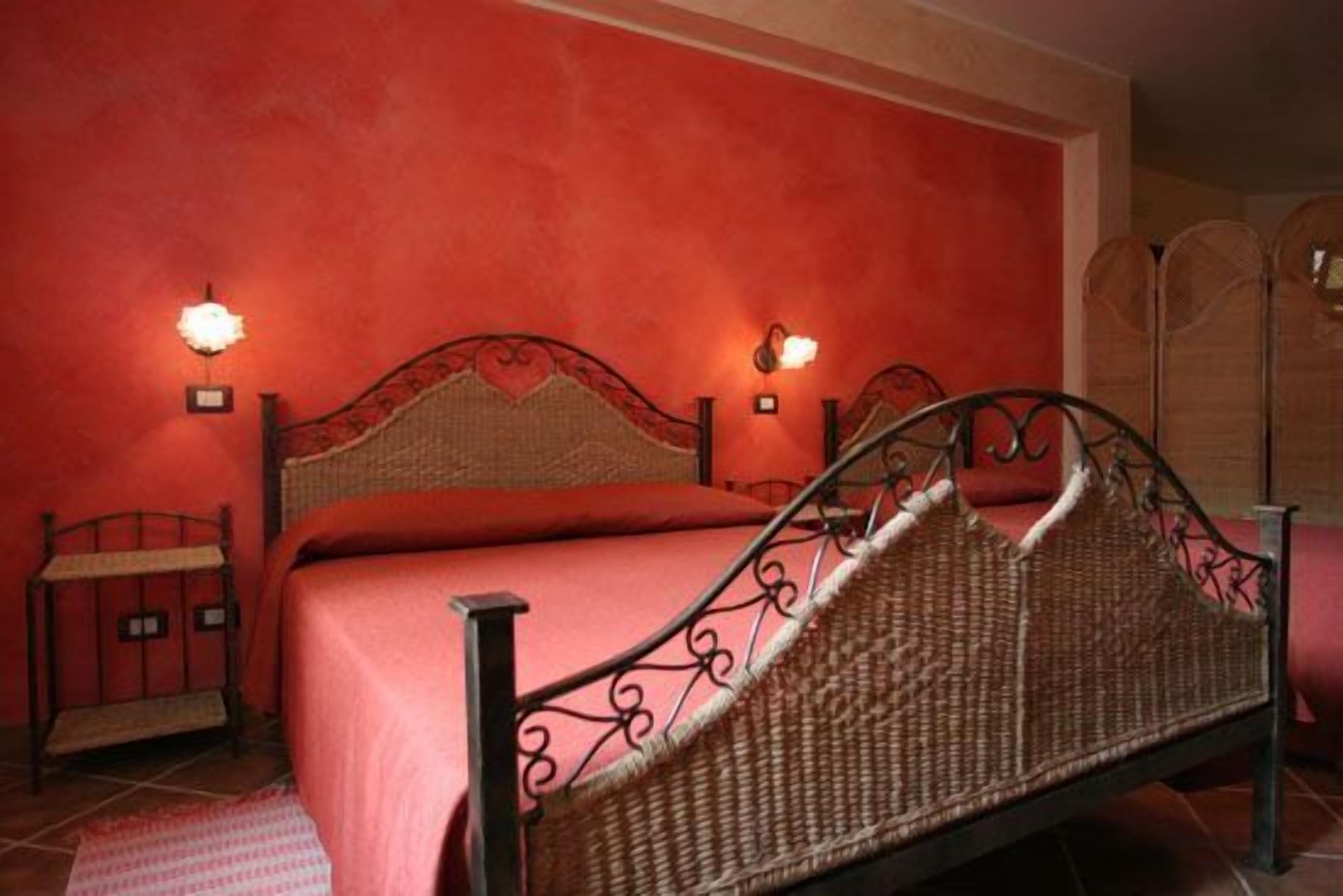 A room with a bed, two wall-mounted lamps, and a small table.