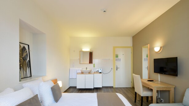A hotel room with a bed, a desk, a TV, and a bathroom. - Hotel du Marche (Lausanne)