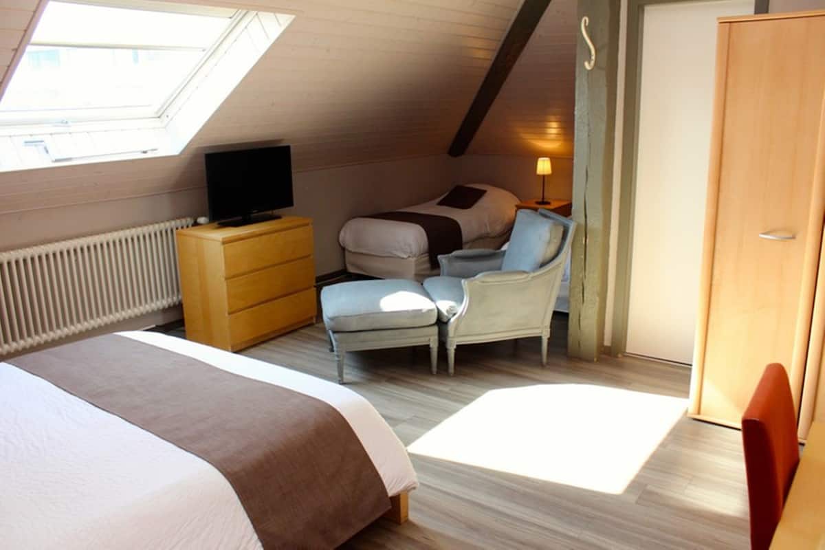A bedroom with a bed, a chair, a TV, a dresser, and a wardrobe.