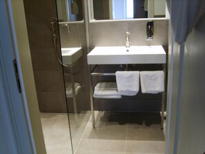 A modern bathroom with a glass shower enclosure, a white sink, and a towel rack. - Schnookeloch (Heidelberg)