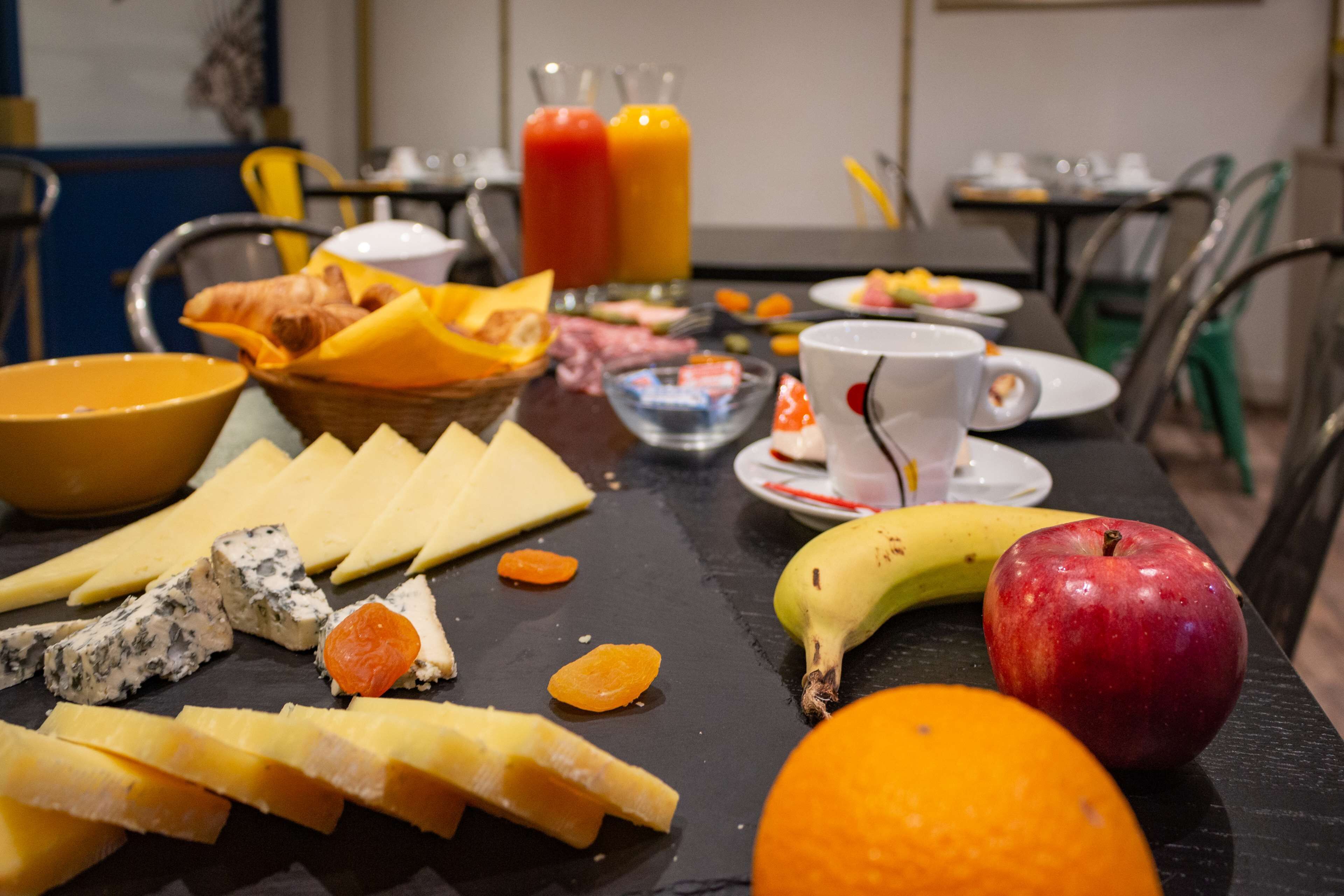 A breakfast setting with cheese, fruits, and juice glasses on a table.