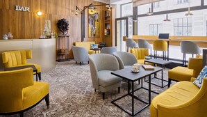 A modern bar area with wooden paneling, a zebra painting, and seating with yellow and grey chairs. - Best Western Hotel Graslin (Nantes)