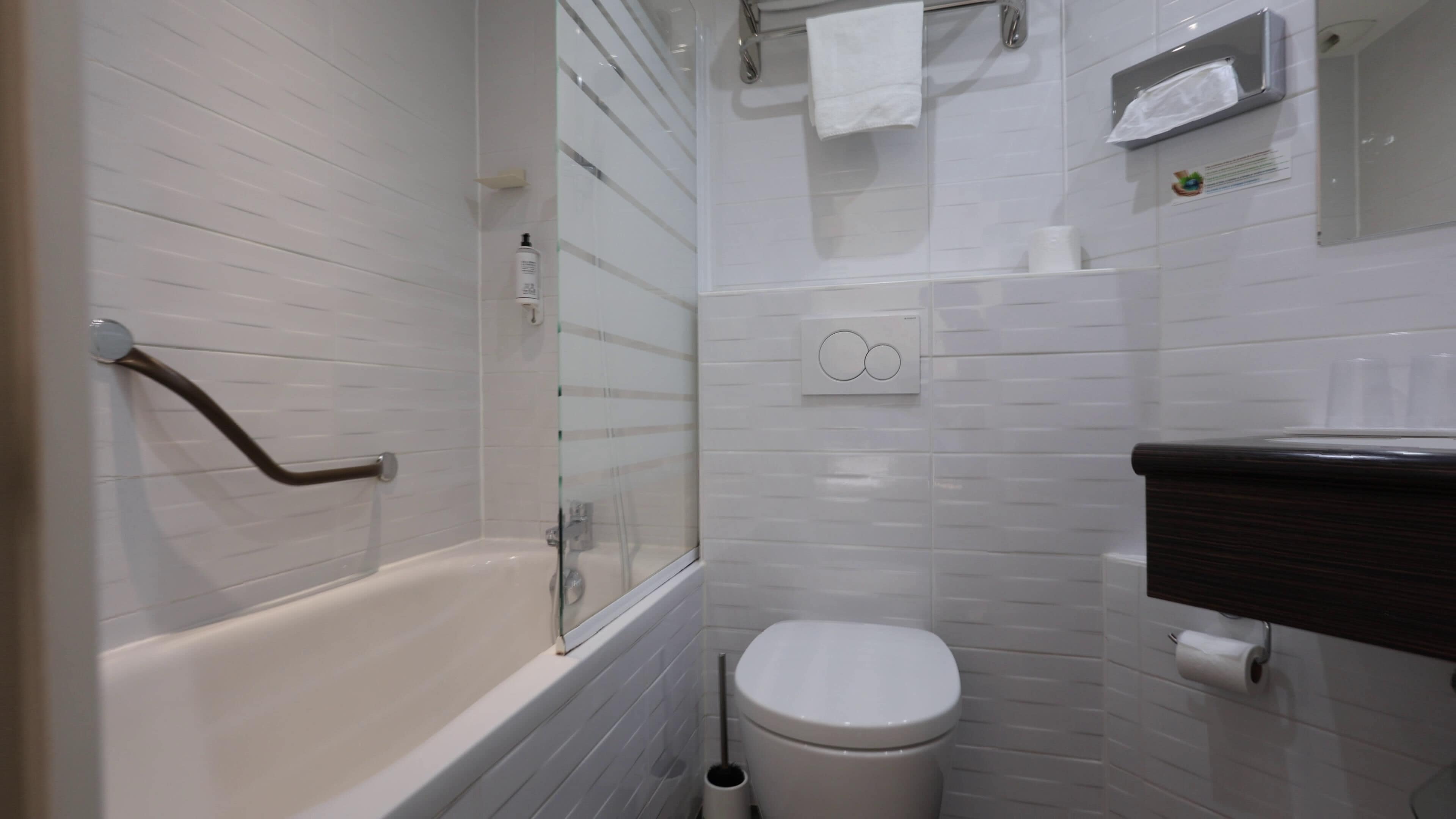 Un bagno con vasca, WC e box doccia in vetro.