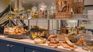 A bakery display with various breads, pastries, and jars of nuts and dried fruits. - Best Western Hotel Graslin (Nantes)