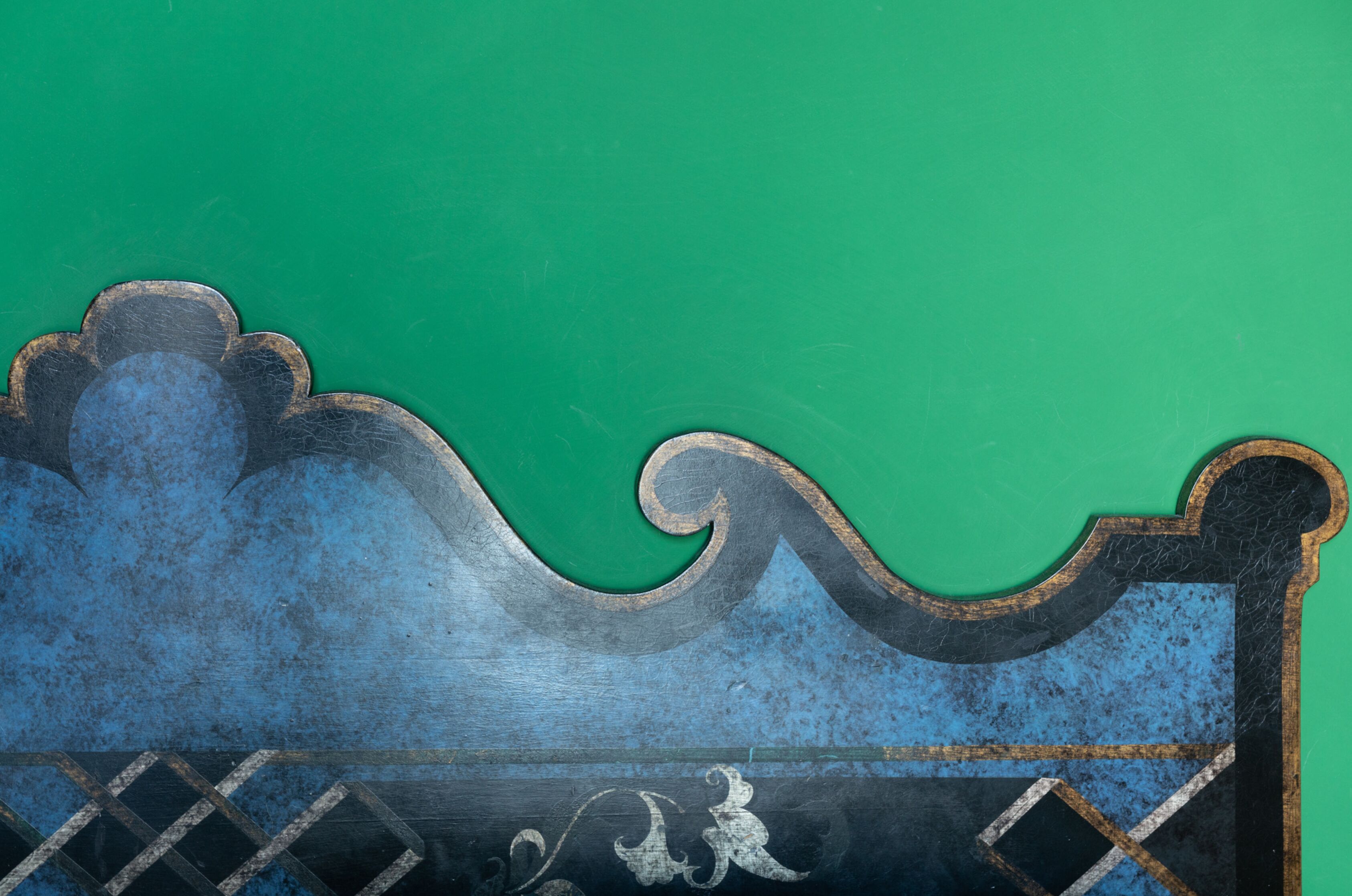 Una pared verde con un panel decorativo azul y negro que muestra una figura blanca.