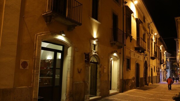Vista nocturna de una calle con edificios que presentan arcos en las puertas y balcones.