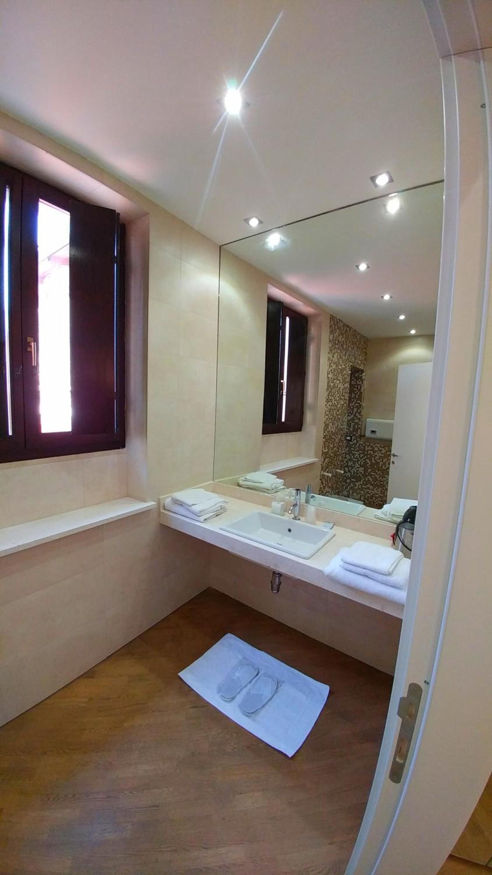 A modern bathroom with a large mirror, two sinks, and a wooden floor.