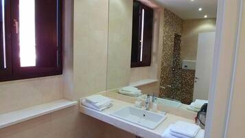 A modern bathroom with a large mirror, two sinks, and a wooden floor.