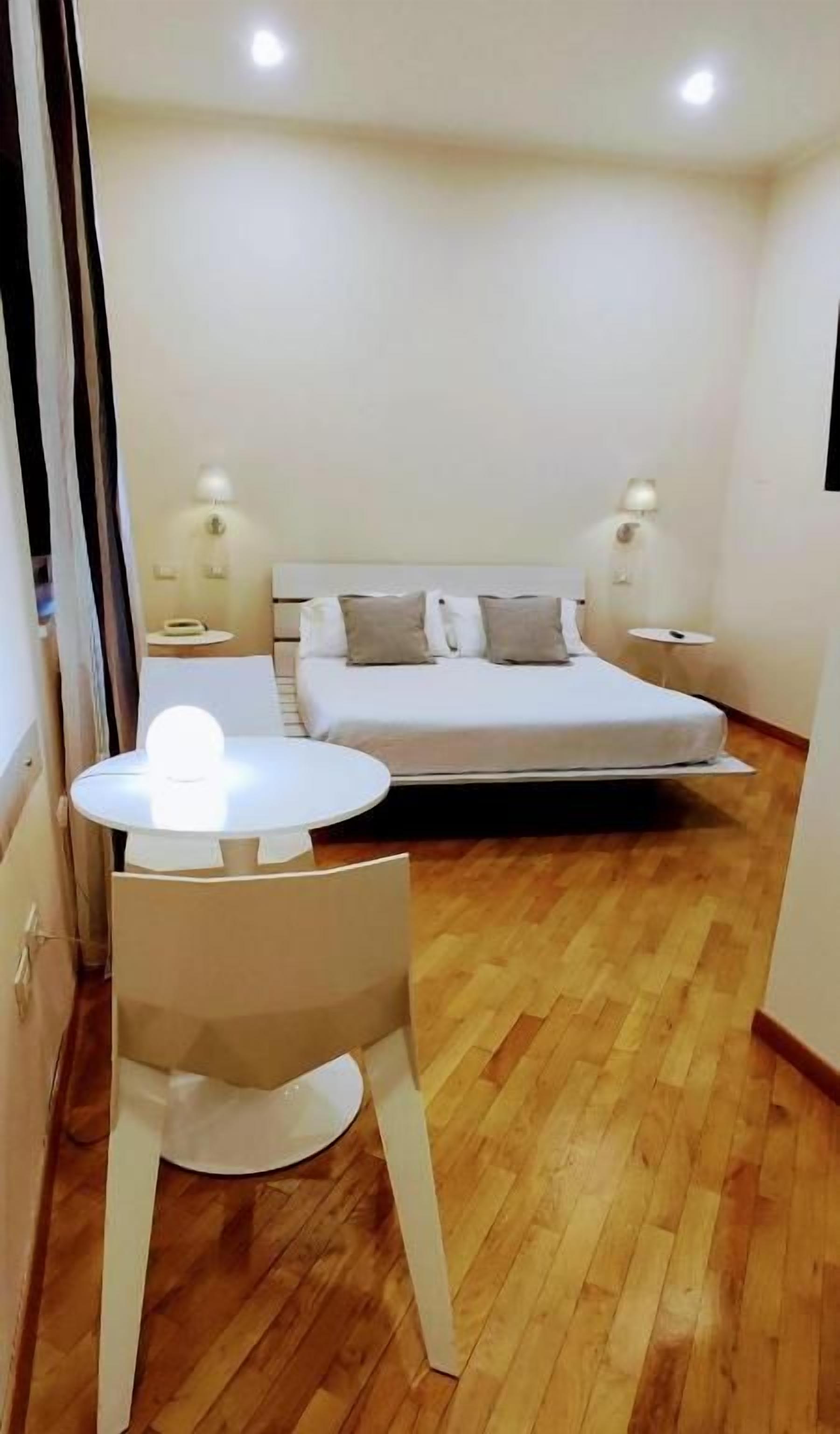Een slaapkamer met een bed, nachtkastjes, een ronde tafel en een stoel.