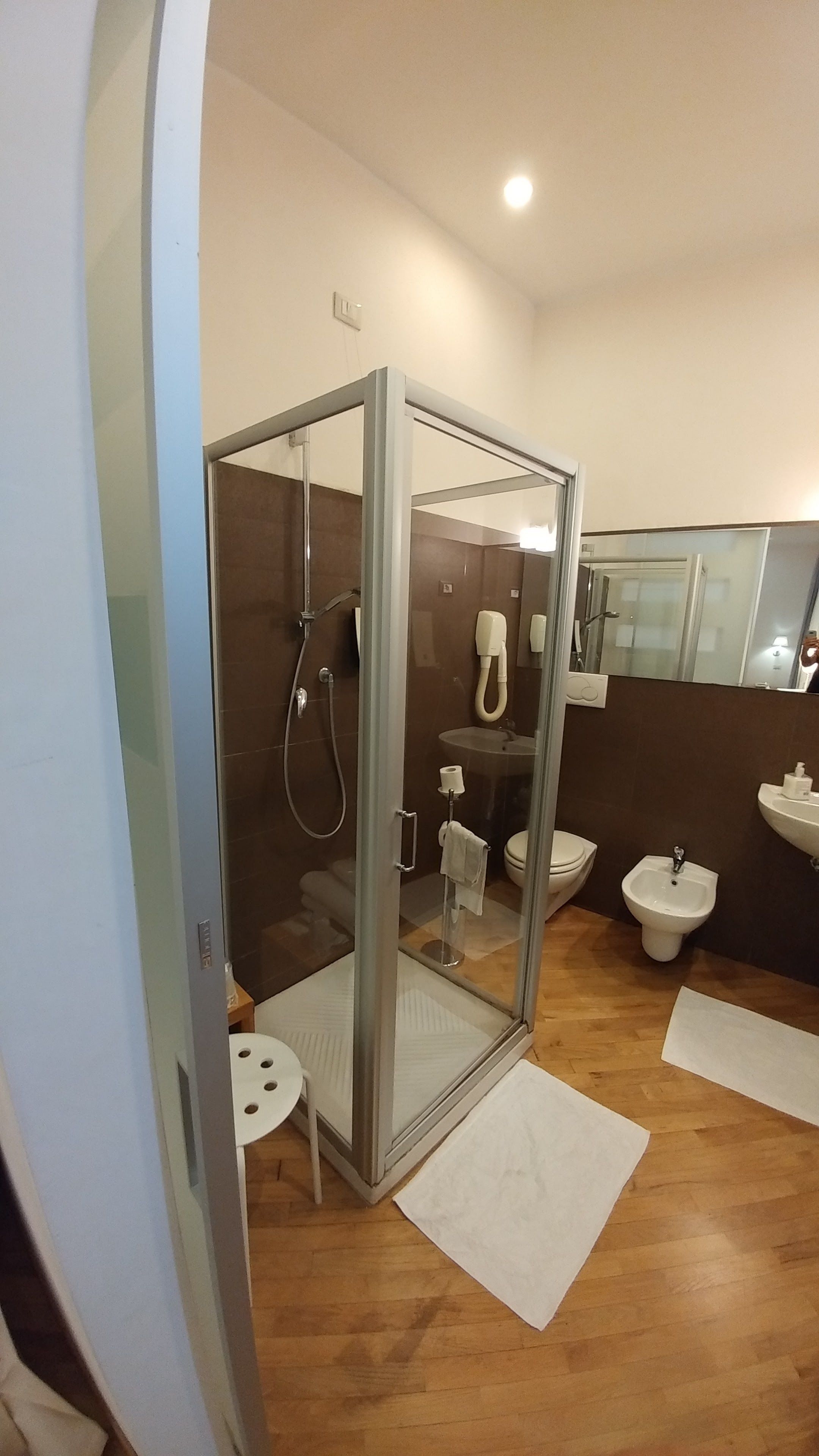Un bagno moderno con doccia vetro, lavandino e water.
