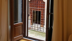 Una habitación con un ventanal grande, suelo de madera y vistas a un espacio exterior con una estructura de ladrillo y un arco decorativo.