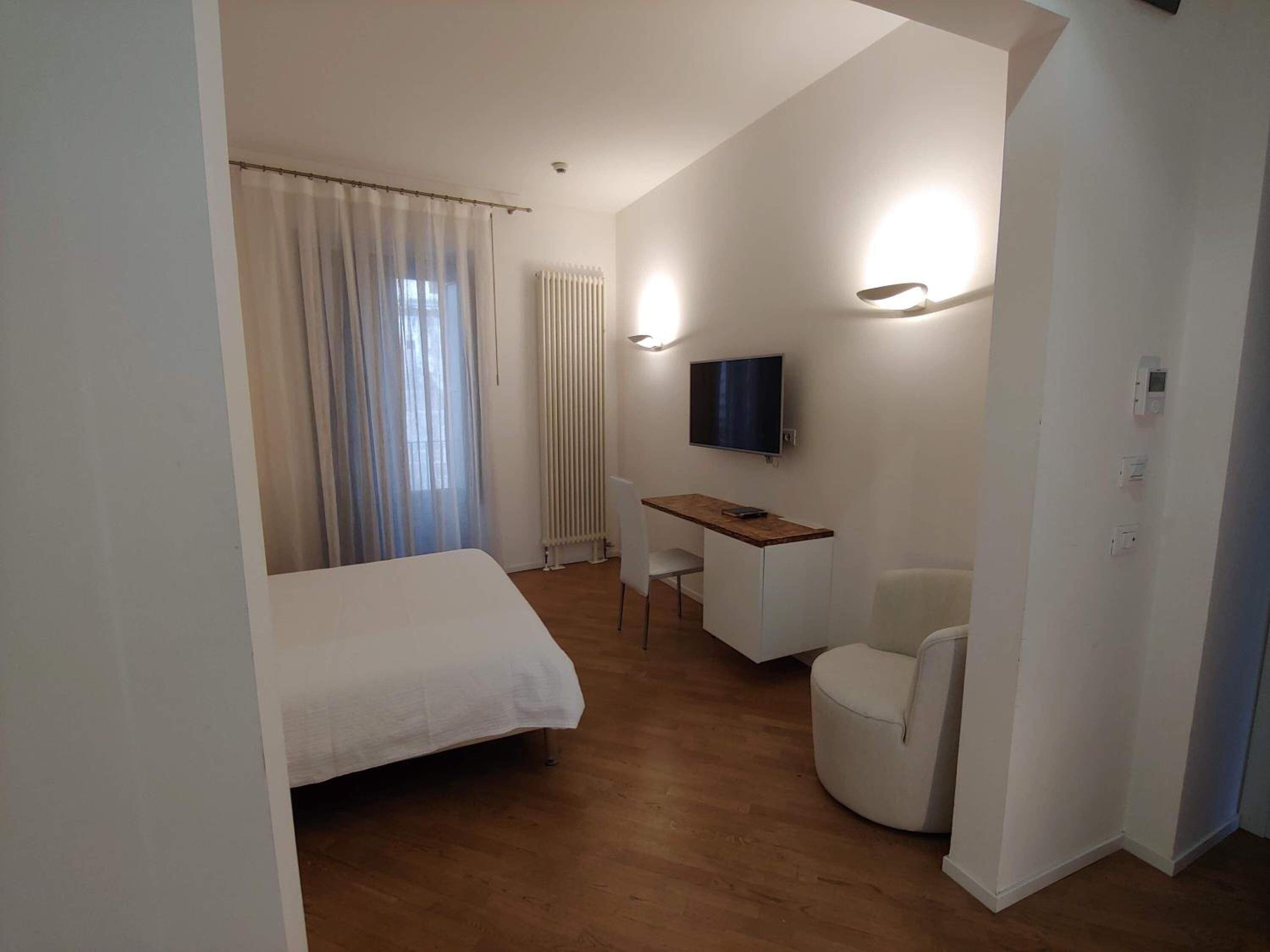 Une chambre d’hôtel équipée d’un lit, d’un bureau, d’une chaise, d’une télévision et d’un radiateur.