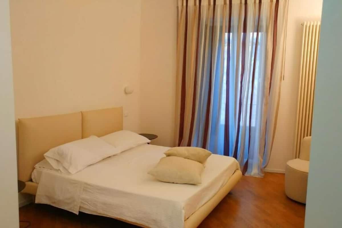 A bedroom with a bed, curtains, and a radiator.