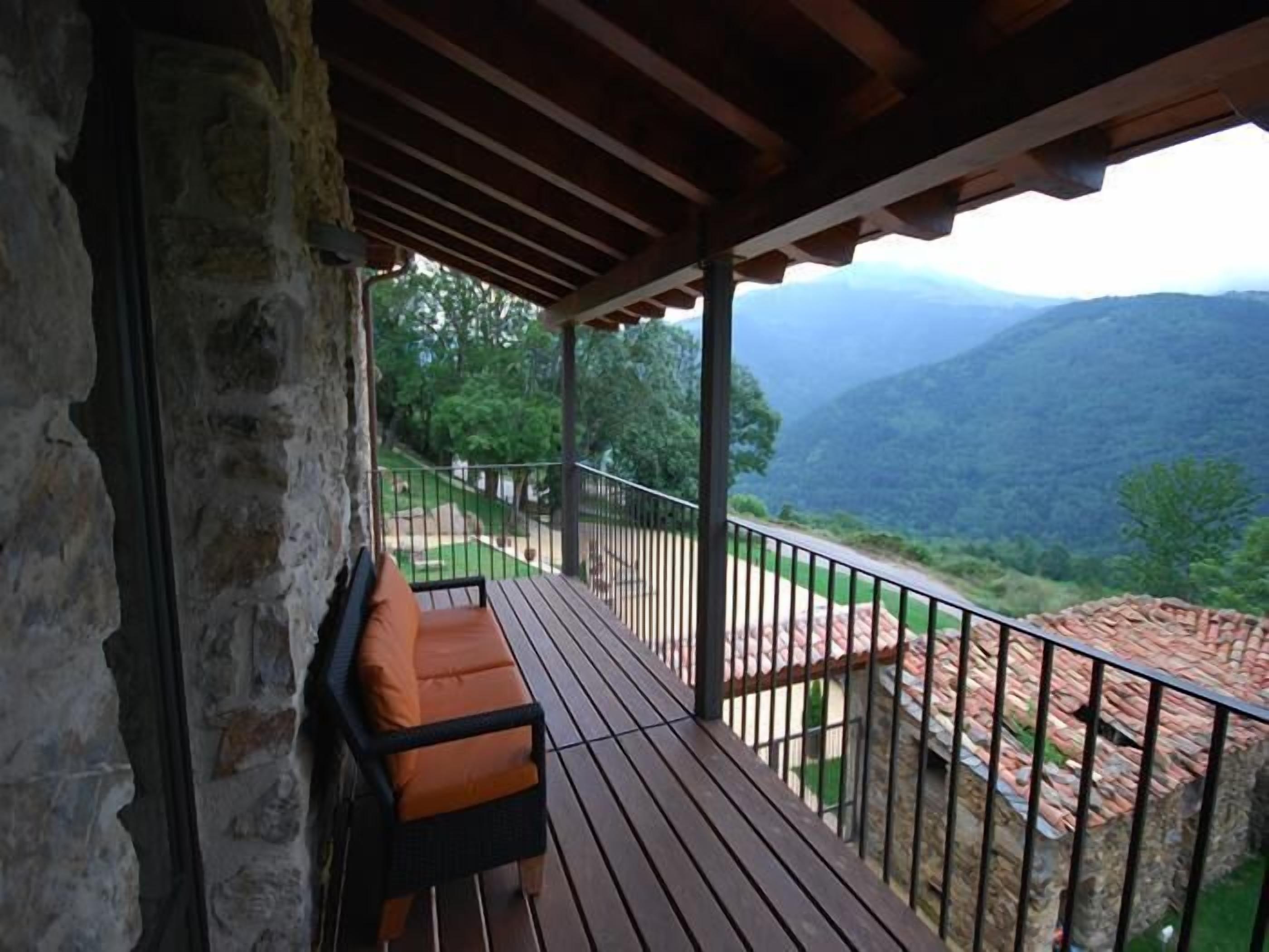 A wooden deck with a bench, stone walls, and a view of mountains.
