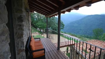 A wooden deck with a bench, stone walls, and a view of mountains.