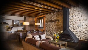 A cozy living area with a stone wall, a fireplace, and wooden furniture. - Rusticae La Casassa de Ribes (Ribes De Freser)