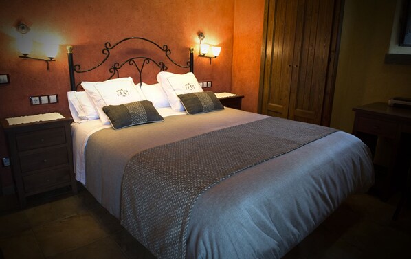 A neatly made bed with a headboard, two bedside tables, and wall-mounted lamps.