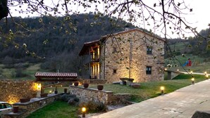 A stone building with a balcony, a paved pathway, and outdoor lighting. - Rusticae La Casassa de Ribes (Ribes De Freser)