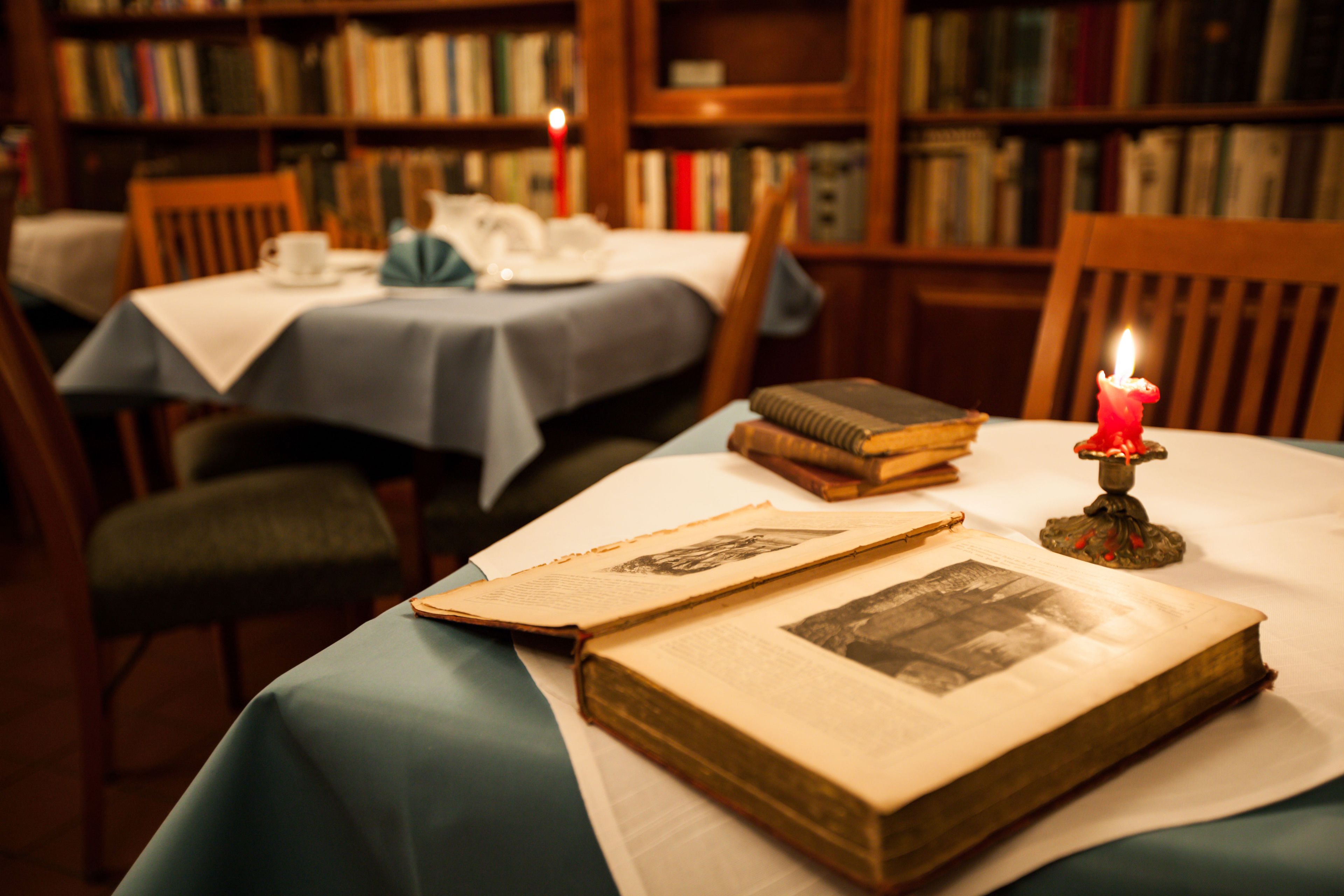 A study room with a table covered by a blue tablecloth, books, and a lit candle.