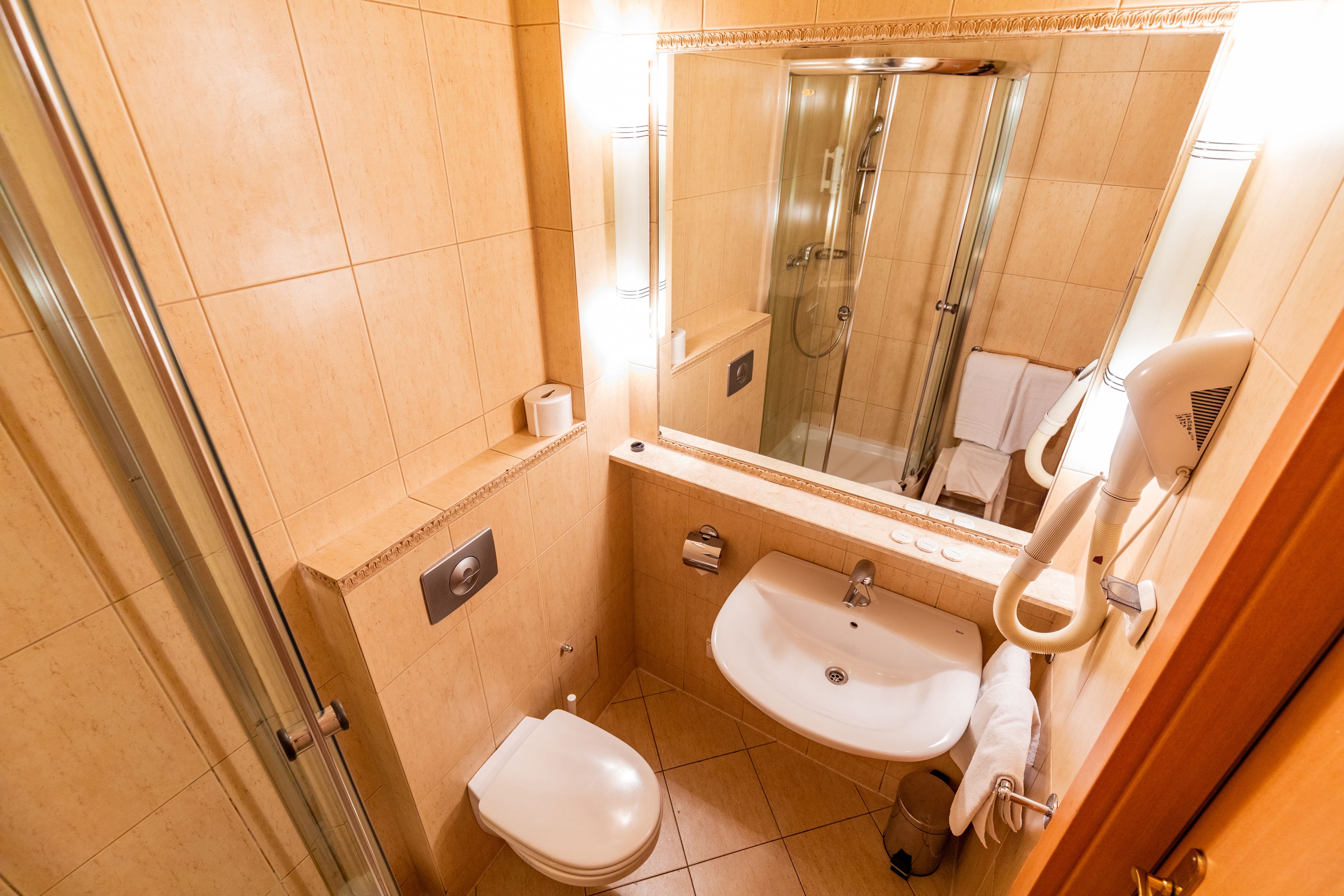 Une salle de bain de taille réduite, dotée d’une douche à parois de verre, d’un lavabo et de toilettes.