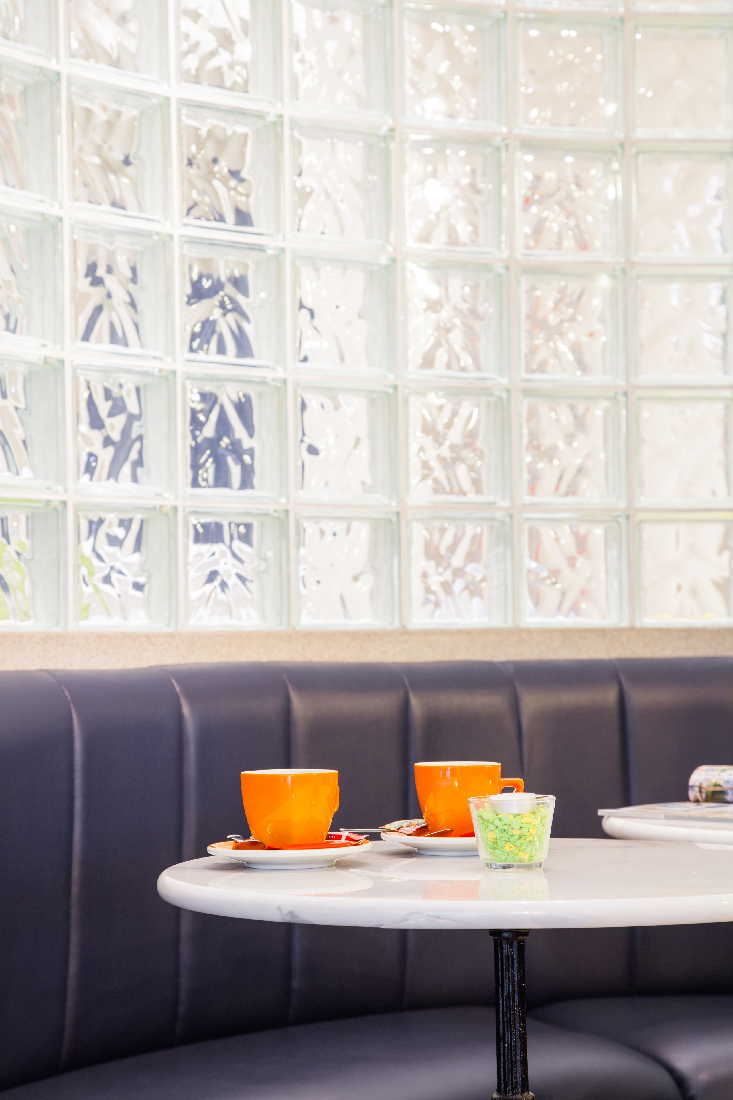 A seating area with a table and chairs, a decorative glass partition, and a cushioned bench.