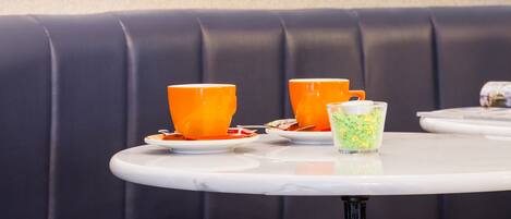 A seating area with a table and chairs, a decorative glass partition, and a cushioned bench.