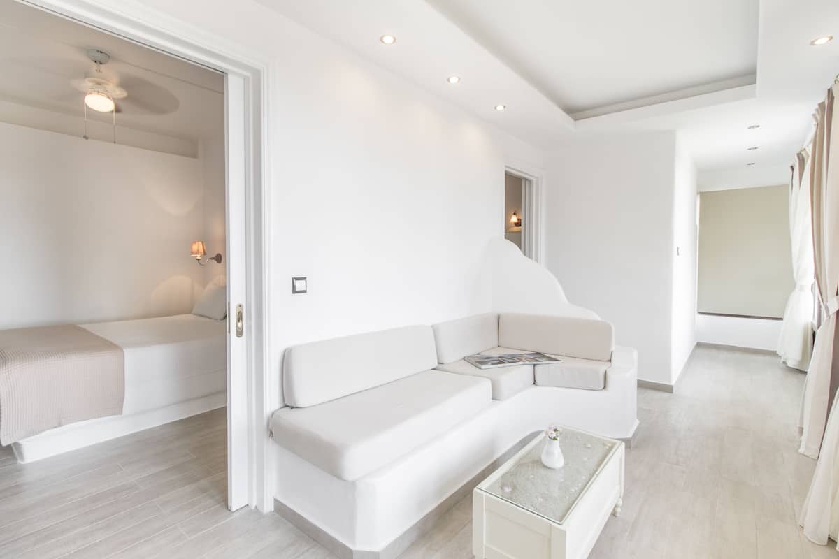 A modern, minimalist living room with a white sofa, a small coffee table, and a ceiling fan.