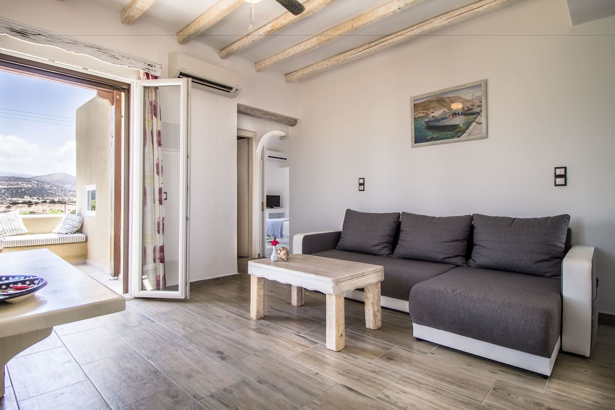 A modern living room with a wooden floor, a sofa, a coffee table, and a painting on the wall.