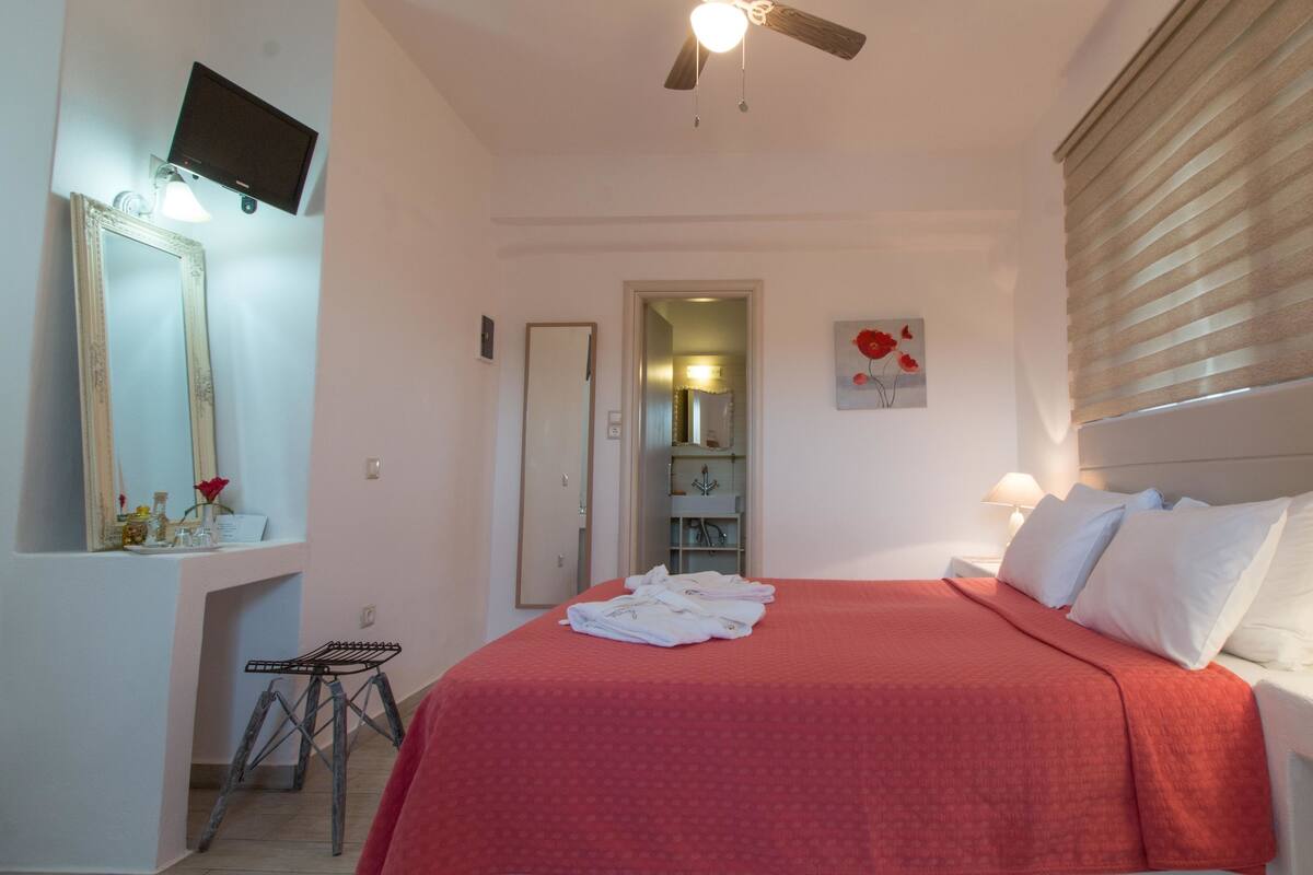 A hotel room with a bed, bedside table, lamp, and a ceiling fan.