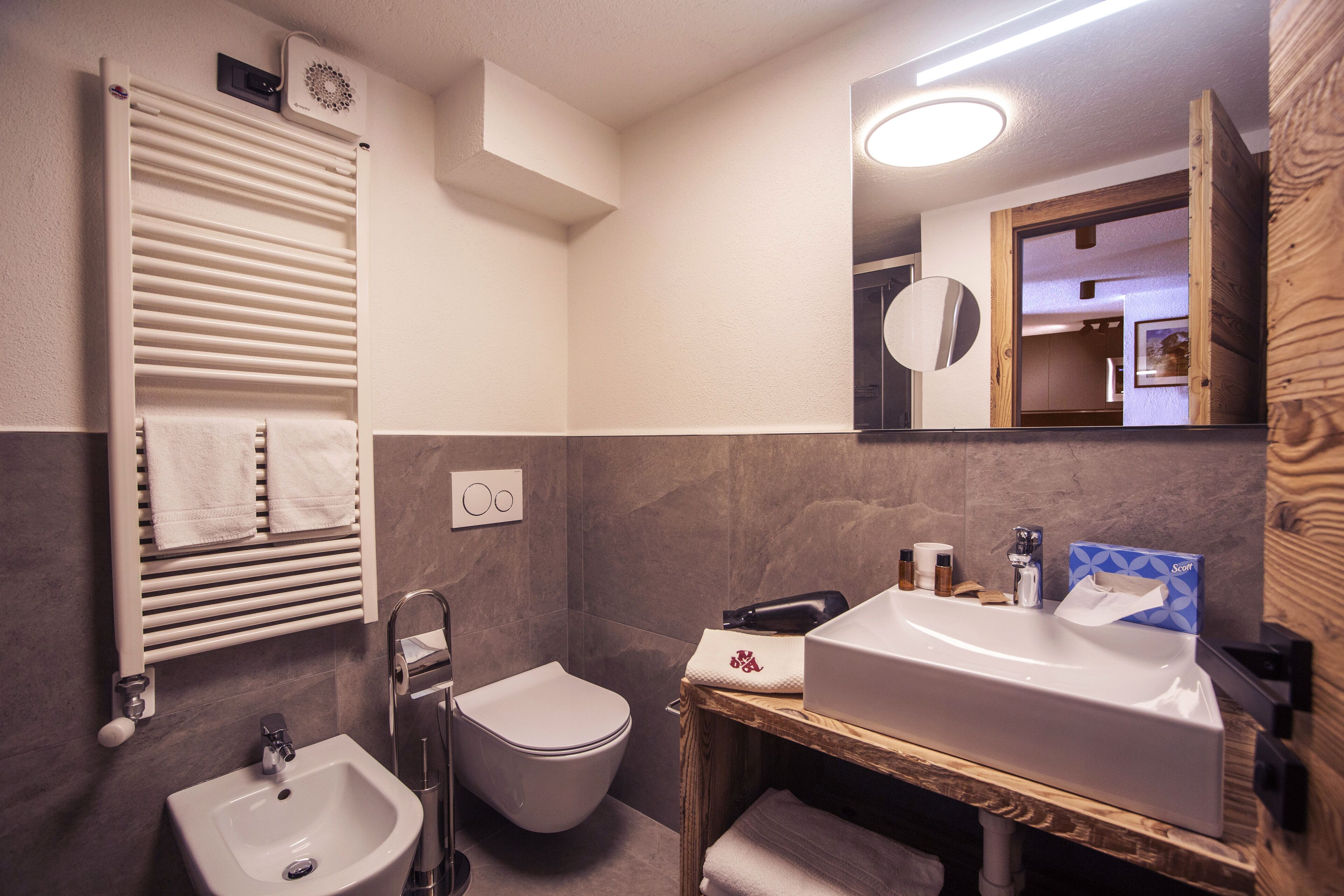 Une salle de bain avec un lavabo blanc, des toilettes, un porte-serviettes et un miroir.