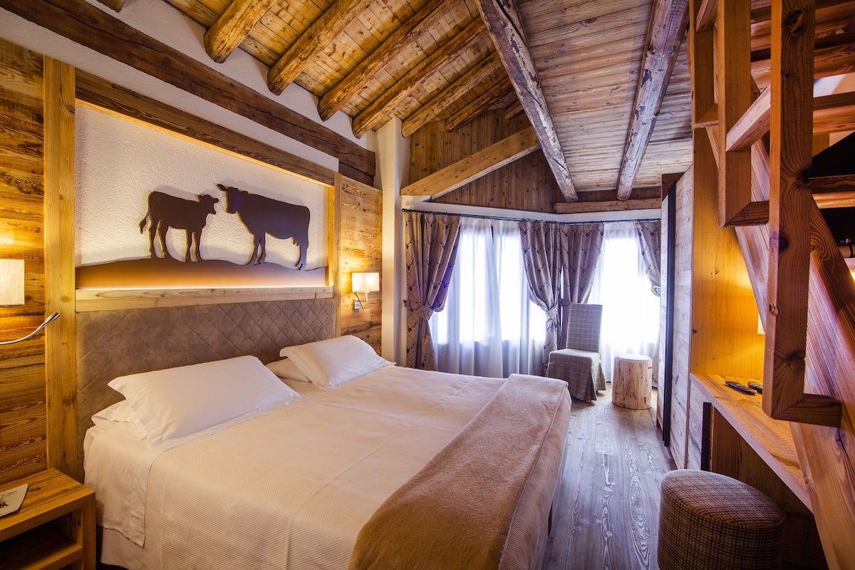 A wooden room with a bed, a headboard with a cow silhouette, and a wooden bench.