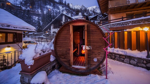 A wooden cabin with a circular entrance, surrounded by snow and a mountain backdrop. - Pilier d'Angle (Courmayeur)