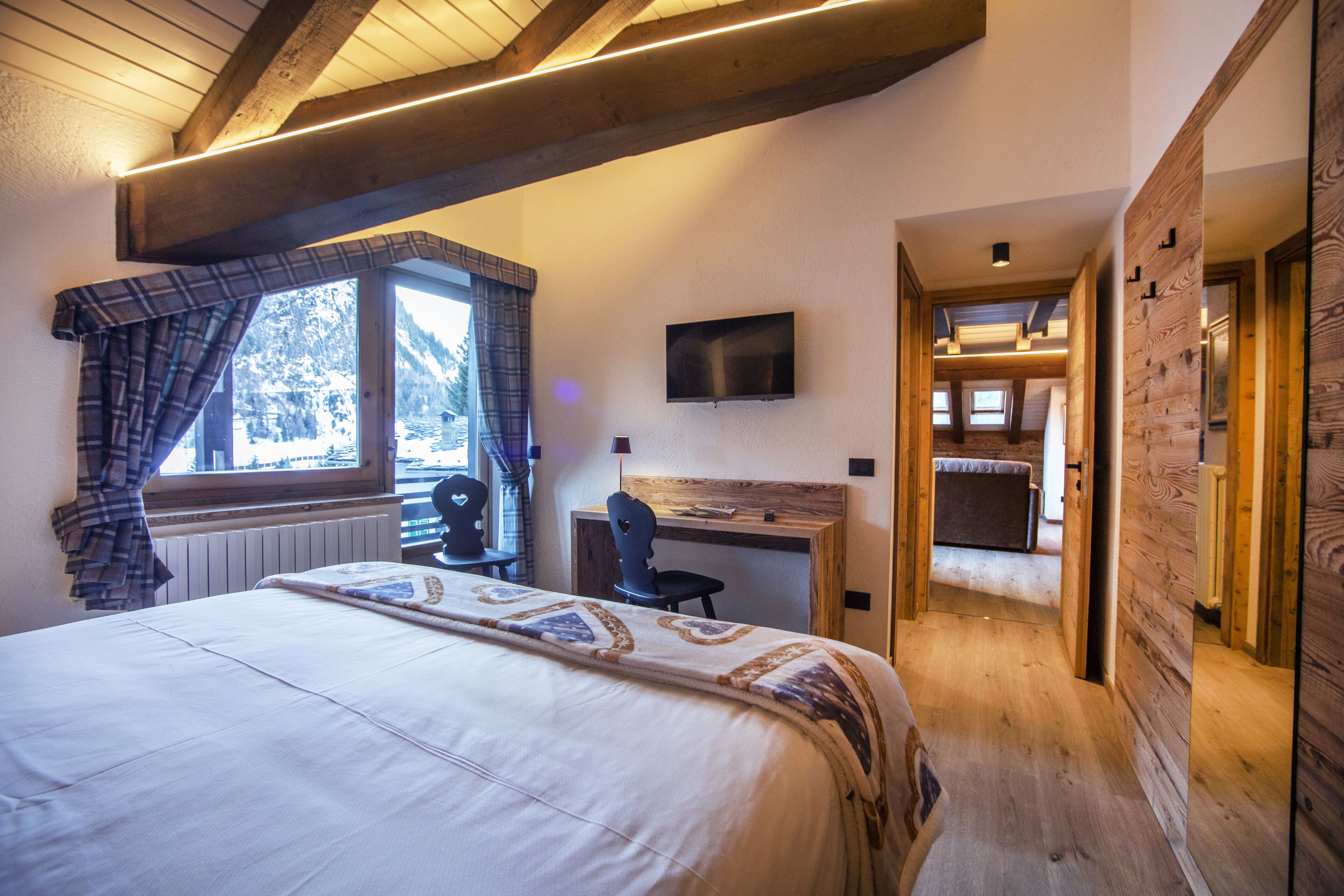 Un dormitorio con cama, escritorio, silla y televisor.