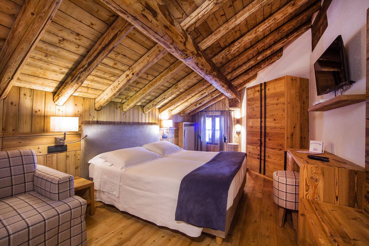 A cozy wooden room with a bed, a sofa, and a small table.