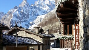 A cozy outdoor seating area with stone walls and a view of snow-capped mountains. - Pilier d'Angle (Courmayeur)