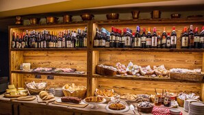 A bar area with multiple shelves of wine bottles and a variety of food and drink items. - Pilier d'Angle (Courmayeur)