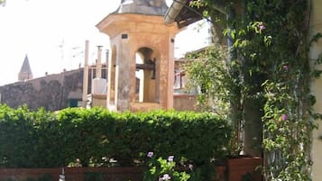 Un clocher surmonté d’un dôme, entouré d’une végétation luxuriante et de plantes en fleurs.