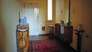 A hallway with a wooden cabinet, a mirror, and a red patterned rug. - Bed and Breakfast Kemonia (Palermo)