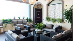 A modern lounge area with wicker furniture, potted plants, and decorative lighting. - Hotel Silver (Milan)